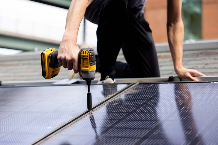Worker drilling a solar panel in place